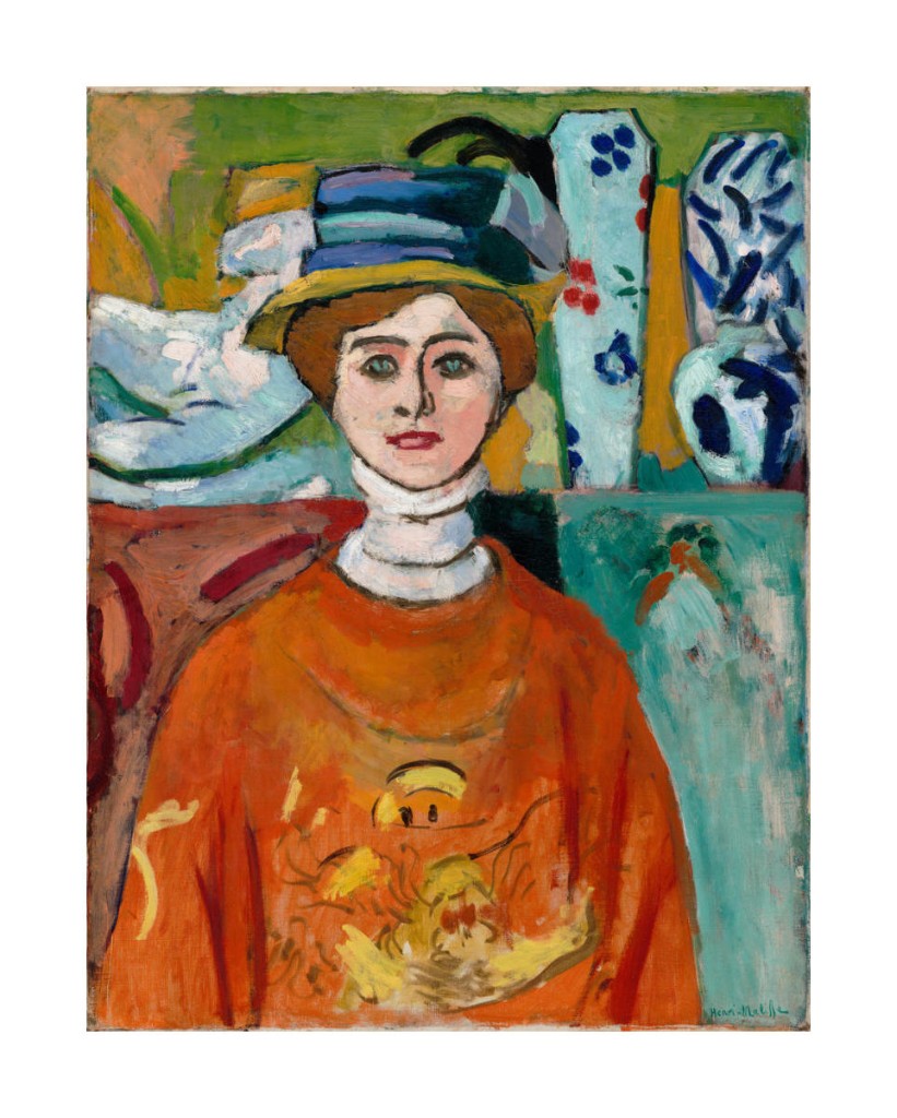 The Girl with Green Eyes de Henri Matisse, 1908. Retrato de una mujer con sombrero azul y prenda rojo-anaranjada, sobre un fondo de colores intensos.