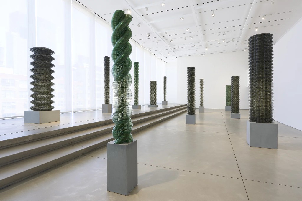 Columnas de discos compactos apilados sobre pedestales, en una galería iluminada por ventanales.